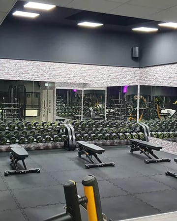 Freihantelbereich im EASYFITNESS-Studio mit Kurzhanteln, Trainingsbänken und großer Spiegelwand