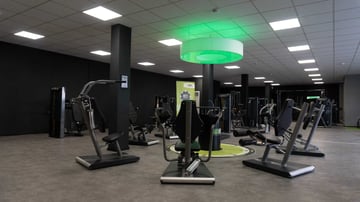 Offener Krafttrainingsbereich im EASYFITNESS-Studio mit modernen Geräten und grünem Deckenelement