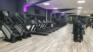 Cardiobereich im EASYFITNESS-Studio mit Laufbändern, Crosstrainern und violetter Beleuchtung