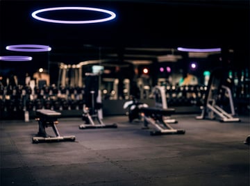 Modernes Fitnessstudio mit Trainingsgeräten und leuchtenden Deckenringen
