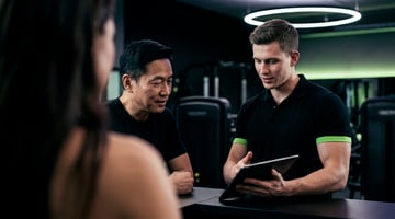 Trainer berät ein Mitglied mithilfe eines Tablets im EASYFITNESS-Studio