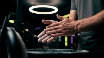 Sportler reibt sich im Fitnessstudio Magnesium an die Hände