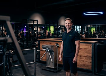 Mitarbeiter im Eingangsbereich eines EASYFITNESS-Studios mit Drehkreuz und Empfangstresen