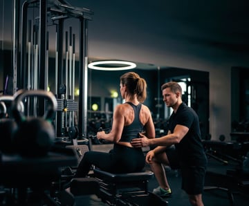 Trainer unterstützt eine Frau beim Krafttraining an einem Fitnessgerät im EASYFITNESS-Studio