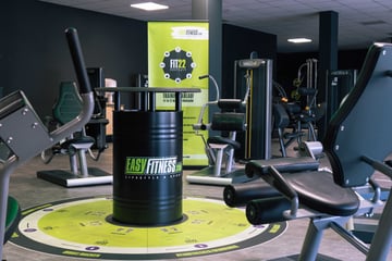 Krafttrainingsbereich im EASYFITNESS-Studio mit Trainingsgeräten und zentralem Markenaufsteller