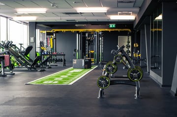 Functional-Training-Bereich mit Kunstrasenbahn, Langhanteln und Kraftgeräten in einem EASYFITNESS Studio